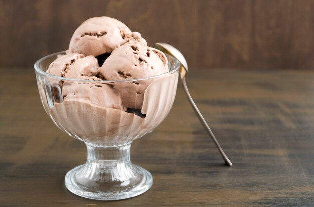 Gelato al cioccolato in un vaso di vetro. su uno sfondo di legno.