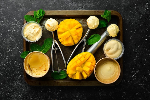 Gelato al mango con menta e mango fresco Cucchiaio gelato su uno sfondo di pietra nera vista dall'alto