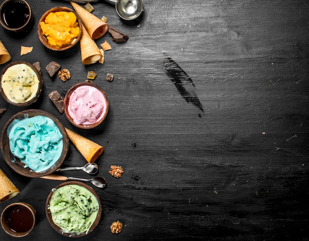 Gelato alla frutta diversa in ciotole con coppe di cialda. Sulla lavagna nera.