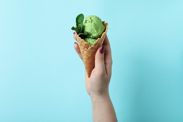 Gelato alla menta della stretta della mano femminile sull'azzurro