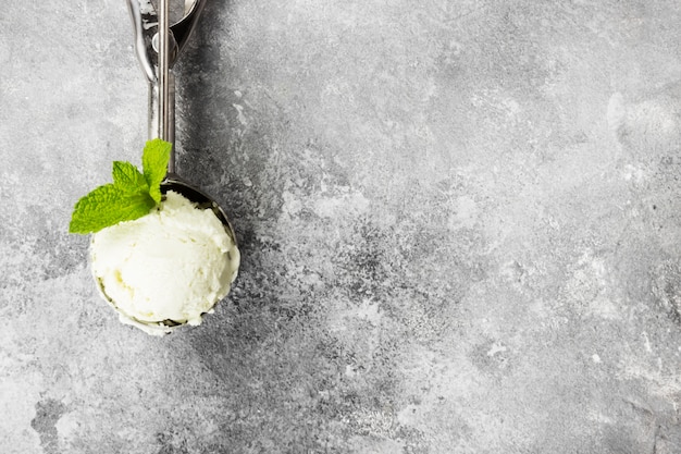 Gelato alla menta in cucchiaio su uno sfondo grigio.