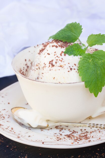 Gelato alla vaniglia con cioccolato croccante in tazza bianca si chiuda