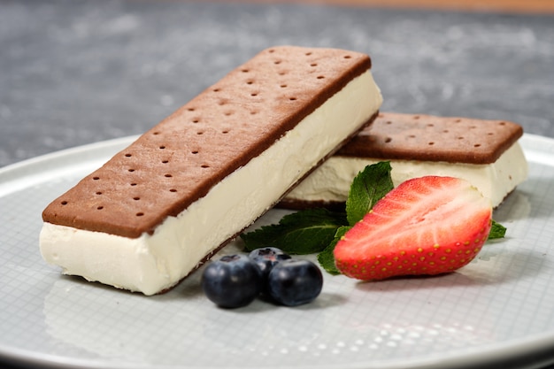 Gelato alla vaniglia con i biscotti su un piatto bianco con le bacche