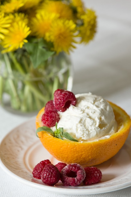 gelato alla vaniglia con lampone dessert estivo delizioso gelato scoop in una metà arancione su un piatto