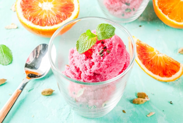 Gelato arancia rossa e sorbetto al cardamomo con arance fresche e fondo azzurro chiaro di menta