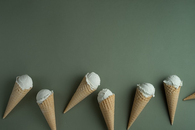 Gelato artigianale in coni di una cialda su sfondo verde. Copia spazio per un testo