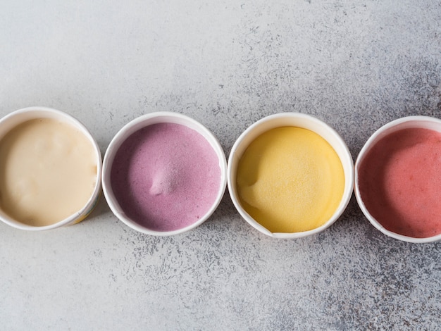 Gelato di frutta fresca di diversi colori in bicchieri di carta su uno sfondo grigio. Vista dall&#39;alto. copia spazio