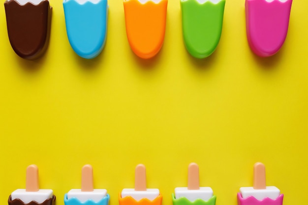Gelato di plastica colorato e vari giocattoli con numeri per bambini su uno sfondo giallo.