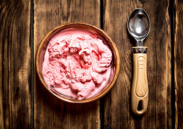 Gelato dolce al lampone con cucchiaio. Su un tavolo di legno.