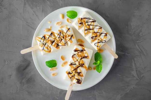 Gelato fatto in casa con torrone e caramello e arachidi su un bastone