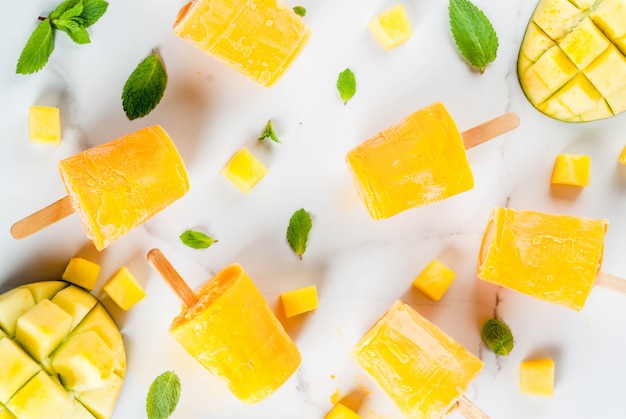 Gelato, ghiaccioli. Alimenti dietetici biologici, dessert. Frullato di mango congelato, con foglie di menta e frutta fresca di mango, su un tavolo di marmo bianco. Copia spazio vista dall'alto