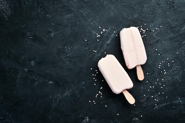 Gelato su un bastoncino con cioccolato bianco su sfondo nero Vista dall'alto Spazio libero per la copia