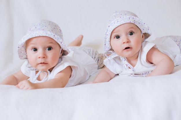 Gemelli felici in cappelli divertenti. Bambini ragazze 7 mesi.