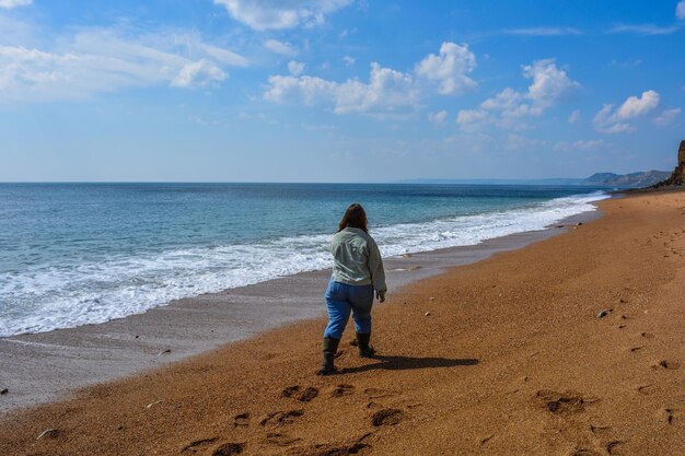 gen_z_woman_from_behind_walking_on_seashore_on_a