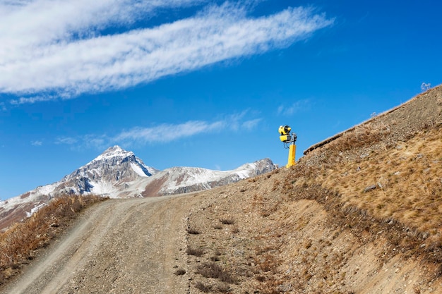 Generatore di neve giallo sul fianco della montagna. Turismo attivo e sport invernali.