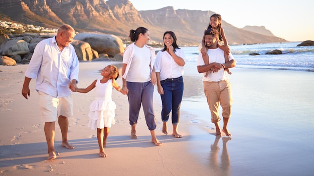 Generazione grande famiglia che cammina sulla spiaggia durante le vacanze estive viaggi e libertà in Sud Africa Sorriso felice e nonni spensierati genitori e bambini rilassano il legame e si godono insieme divertenti vacanze di sole