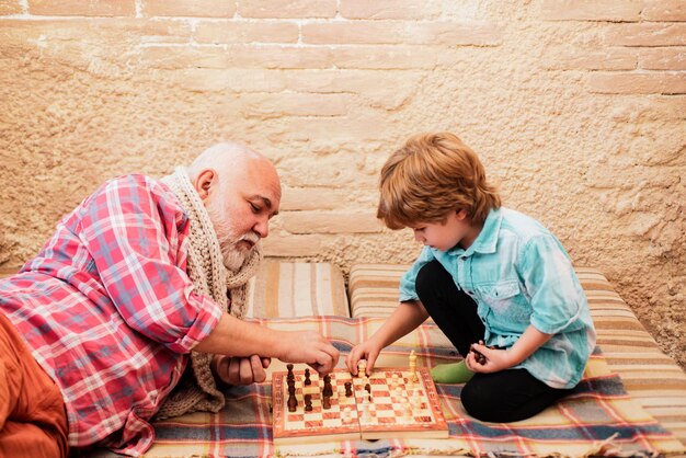 Generazioni scacco matto uomo anziano che insegna a suo nipote a giocare a scacchi pezzo degli scacchi