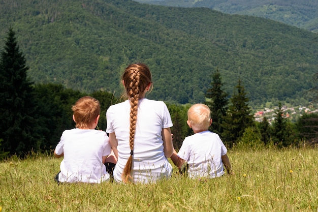 Generi e due giovani figli che si siedono sull'erba