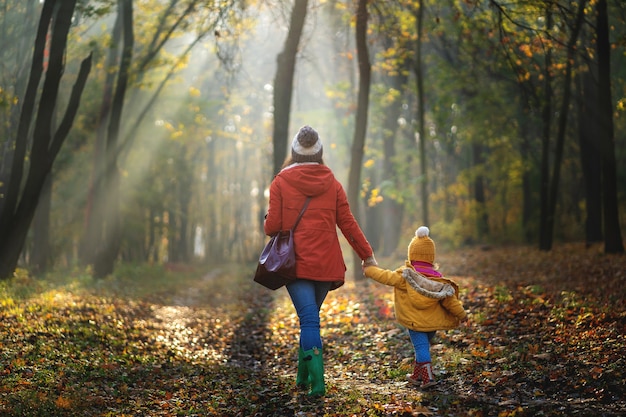 Generi ed il suo bambino su un wallk alla foresta di autunno. Vista posteriore