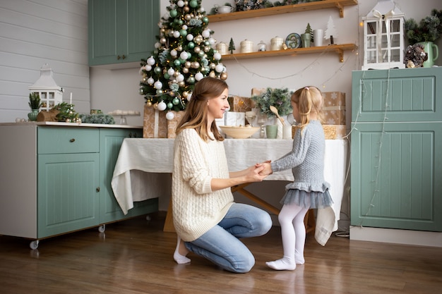 Generi il gioco con il suo bambino nella cucina di Natale a casa.