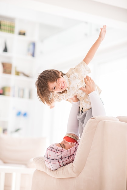 Generi il gioco con il suo piccolo figlio sul sofà a casa