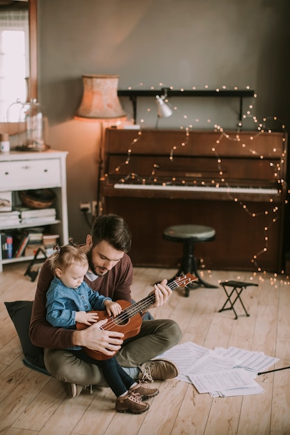 Generi la figlia d&#39;istruzione per giocare la chitarra nella stanza a casa