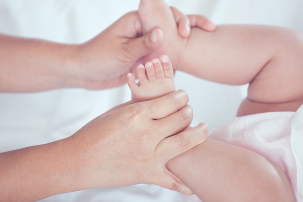 Generi la mano che tiene i piccoli piedi della neonata mentre lei che si trova sul letto