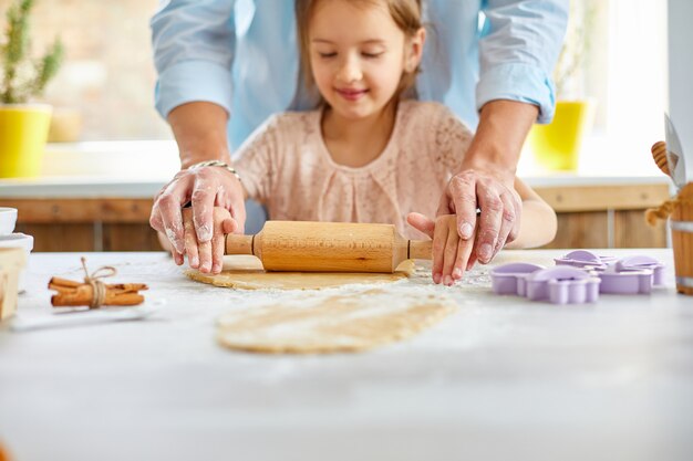 Generi mostrando alla sua piccola figlia come rotolare la pasta per i biscotti