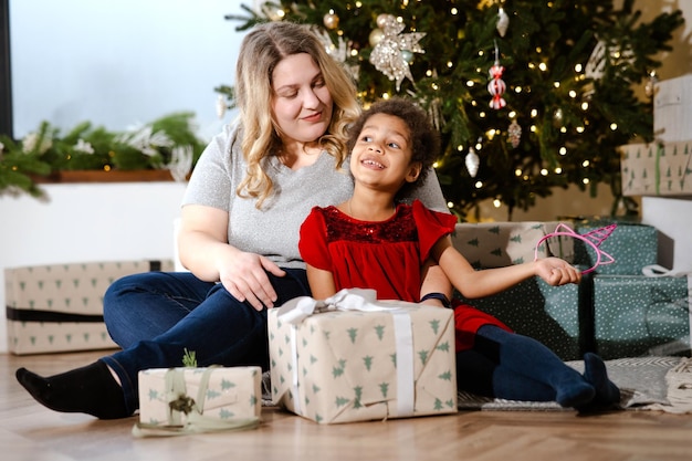 Genitore e bambino che si divertono vicino all'albero di Natale al chiuso.