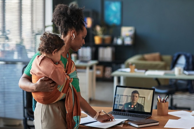 Genitore multitasking che lavora a casa con il bambino