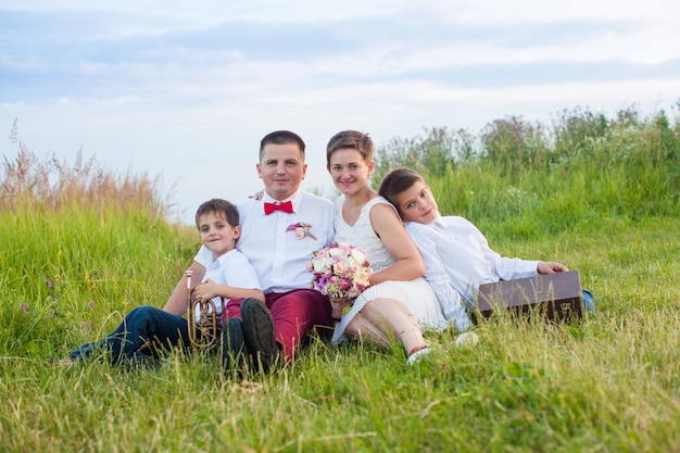 Genitori alla moda nel campo, giorno del matrimonio con i bambini, il ragazzo gioca sul tubo