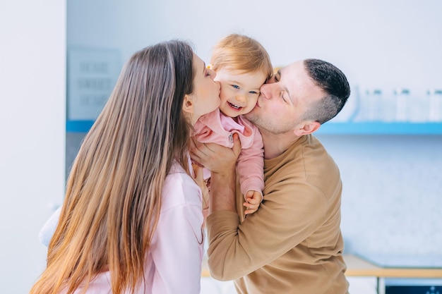 Genitori amorevoli mamma e papà tengono un felice bacio della figlia nelle guance