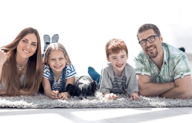 Genitori con bambini sdraiati nel soggiorno sulla foto del tappeto con spazio per la copia