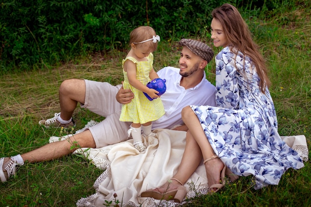 Genitori con figlia che si rilassano all'aperto. Famiglia felice che si diverte al parco.