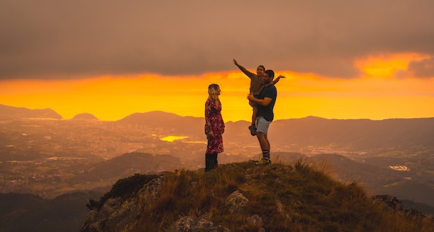 Genitori con il figlio in cima a una montagna al tramonto