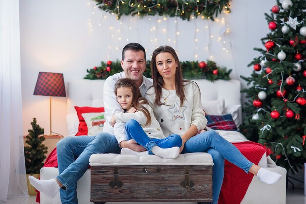 Genitori con il loro bambino seduto vicino all'albero di Natale