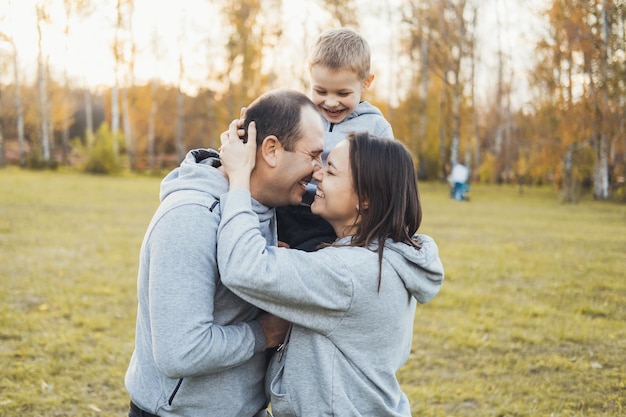 Genitori di mezza età con il loro figlioletto in piedi nel parco all'aperto giorno della famiglia