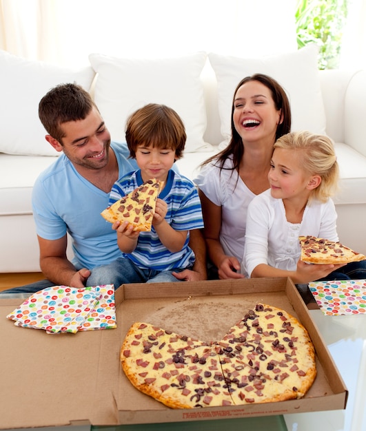 Genitori e bambini che mangiano pizza in salotto