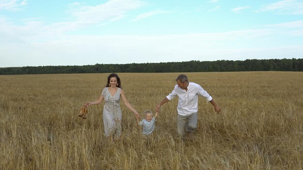 Genitori e bambini corrono attraverso il grano sul campo