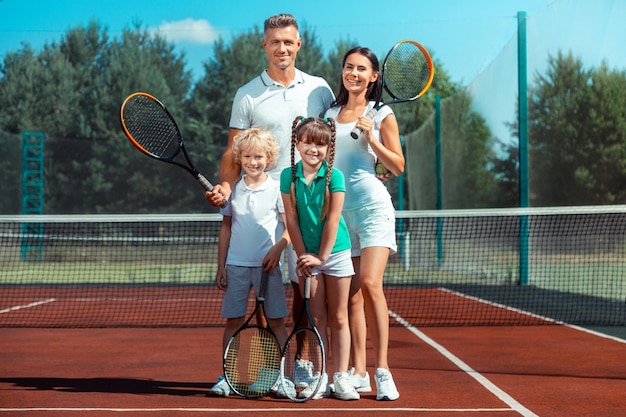 Genitori e bambini felici e allegri dopo aver giocato a tennis