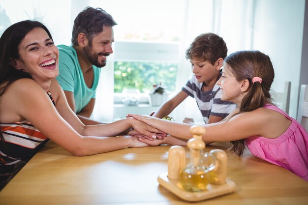 Genitori e figli che uniscono le mani sul tavolo