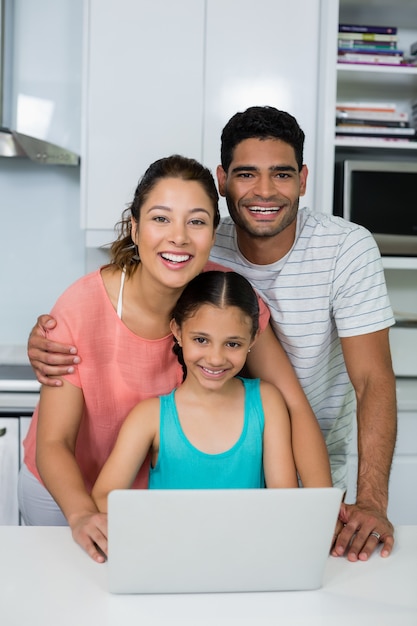 Genitori e figlia che utilizza computer portatile nella cucina a casa