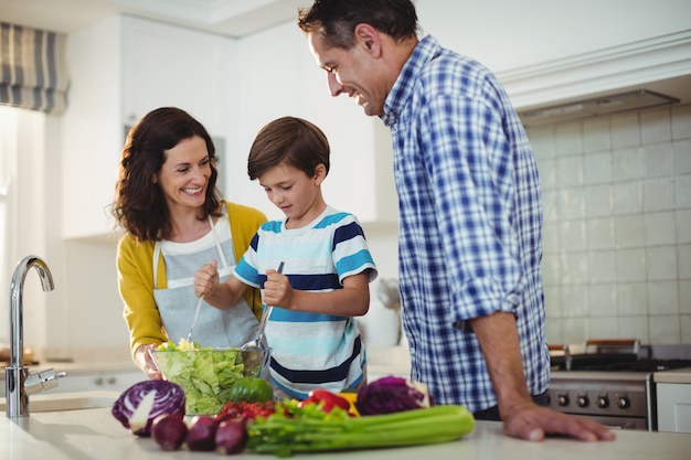 Genitori e figlio che mescolano l'insalata in cucina