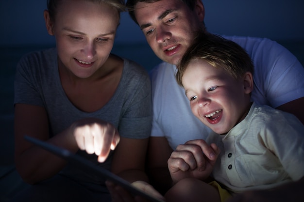 Genitori e figlio con tablet PC all&#39;aperto a tarda sera