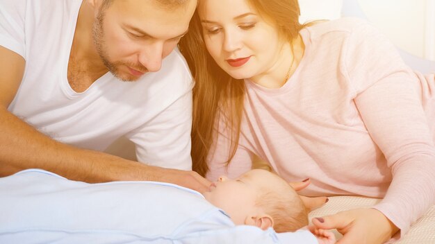 Genitori felici che guardano il dolce bambino addormentato in camera da letto, la luce del sole