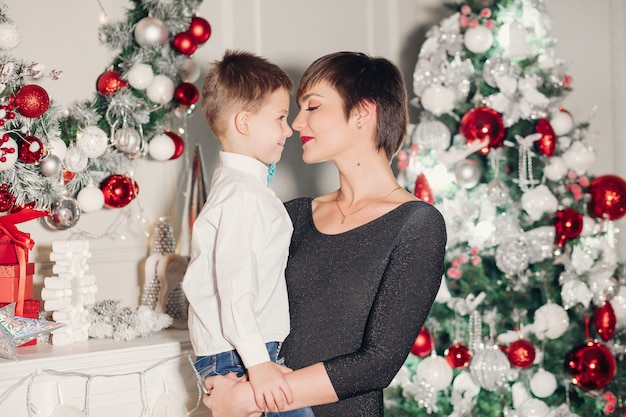 Genitori felici che mostrano la decorazione di natale sull'albero per il piccolo figlio.