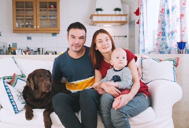 Genitori felici con bambino e cane sul divano a casa interni Lifestyle family concept