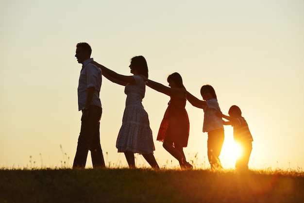 Genitori felici con i bambini all&#39;aperto al tramonto