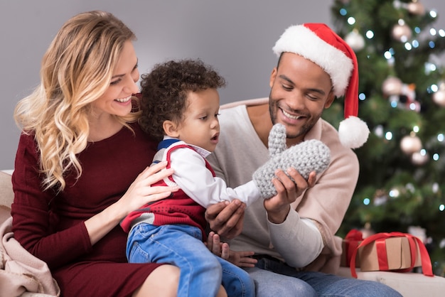 Genitori premurosi. Uomo barbuto felice positivo che tiene un guanto e aiuta suo figlio a indossarlo mentre trascorre del tempo con la sua famiglia