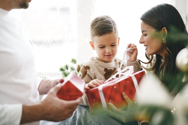 Genitori sorridenti che danno il regalo di Natale al figlio a casa